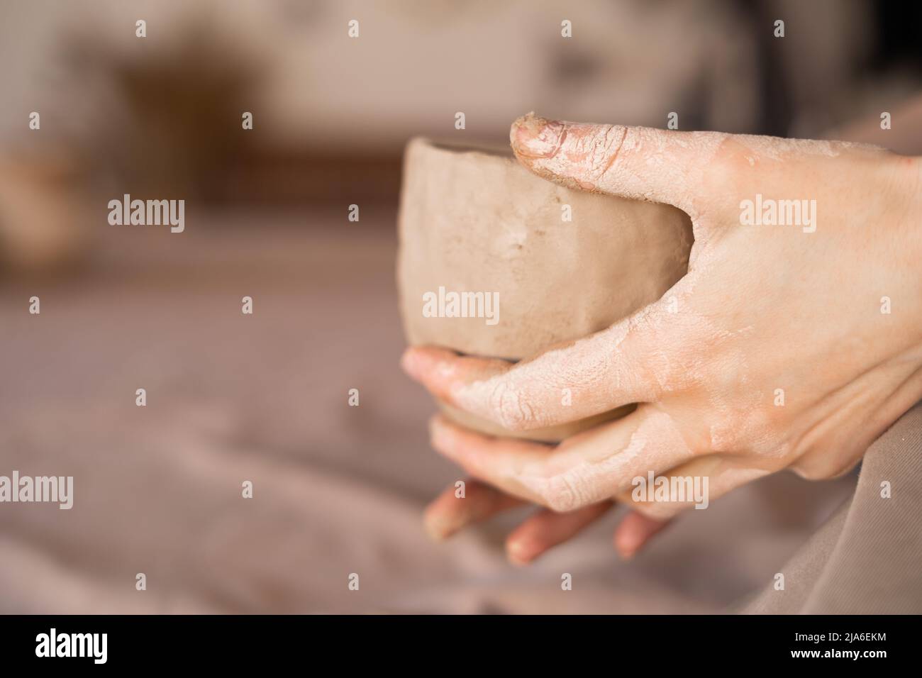 Potter al lavoro. Le mani di Potter in creta formano un vaso in un cerchio. Primo piano di femmina sculpting ciotole da creta bagnata cruda. Foto Stock