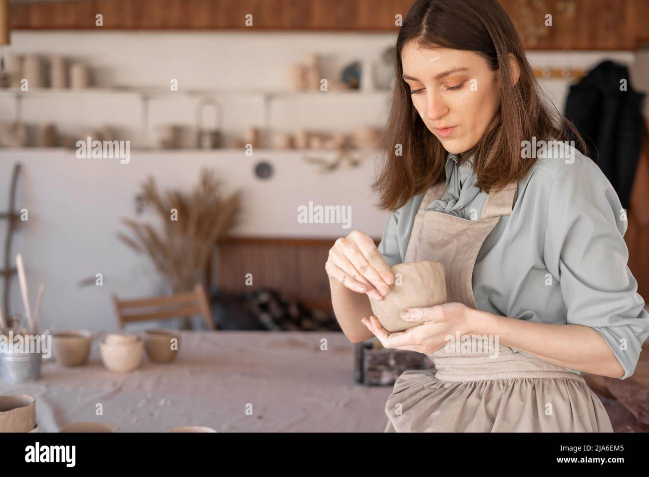 Una giovane madre vasaio femminile in studio scolpisce una pentola di argilla. Banner. Foto Stock