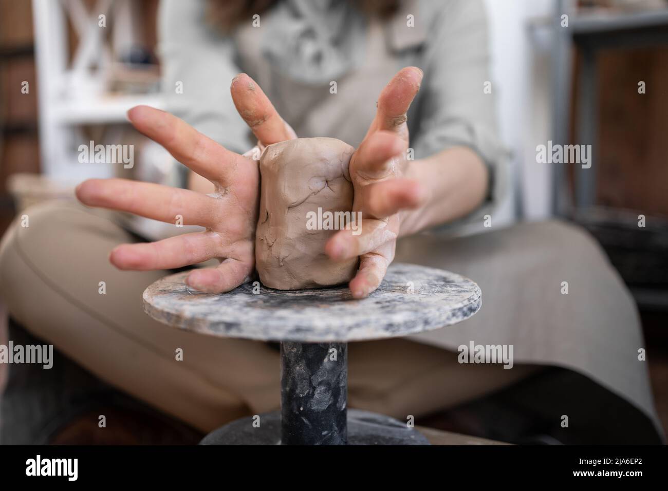 Una donna lavora sulla ruota di un vasaio. Un artigiano forgia una tazza da una pentola di argilla. Officina di stampaggio manuale. Foto Stock