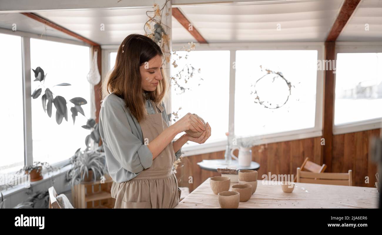 . – artista donna scolpisce da argilla umida in studio. ceramista fa artigianato da ceramica. concetto di industriosità femminile. Foto Stock