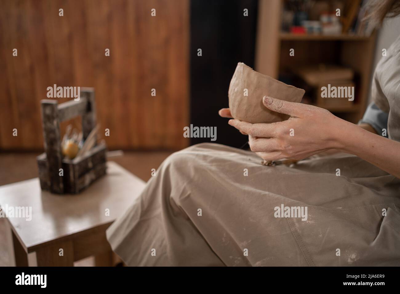 Primo piano di mani femminili che fanno ceramica. Una donna scolpisce una ciotola di argilla bianca, vista laterale. Foto Stock