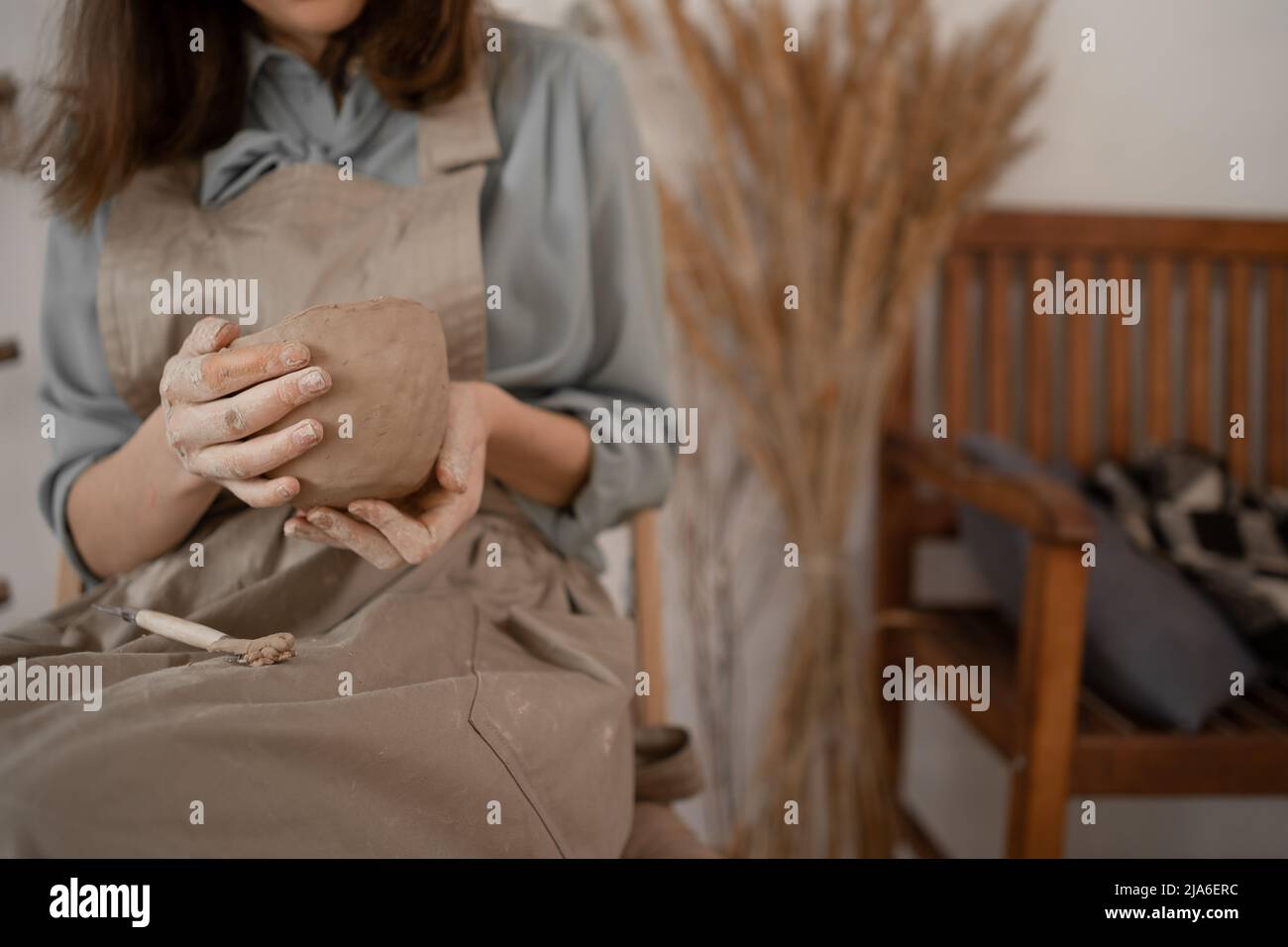 Fai da te il primo piano di una donna creativa che scolpisce una ciotola da argilla grezza in un laboratorio di ceramica durante una lezione o un laboratorio. Artigianato e artigiano Foto Stock