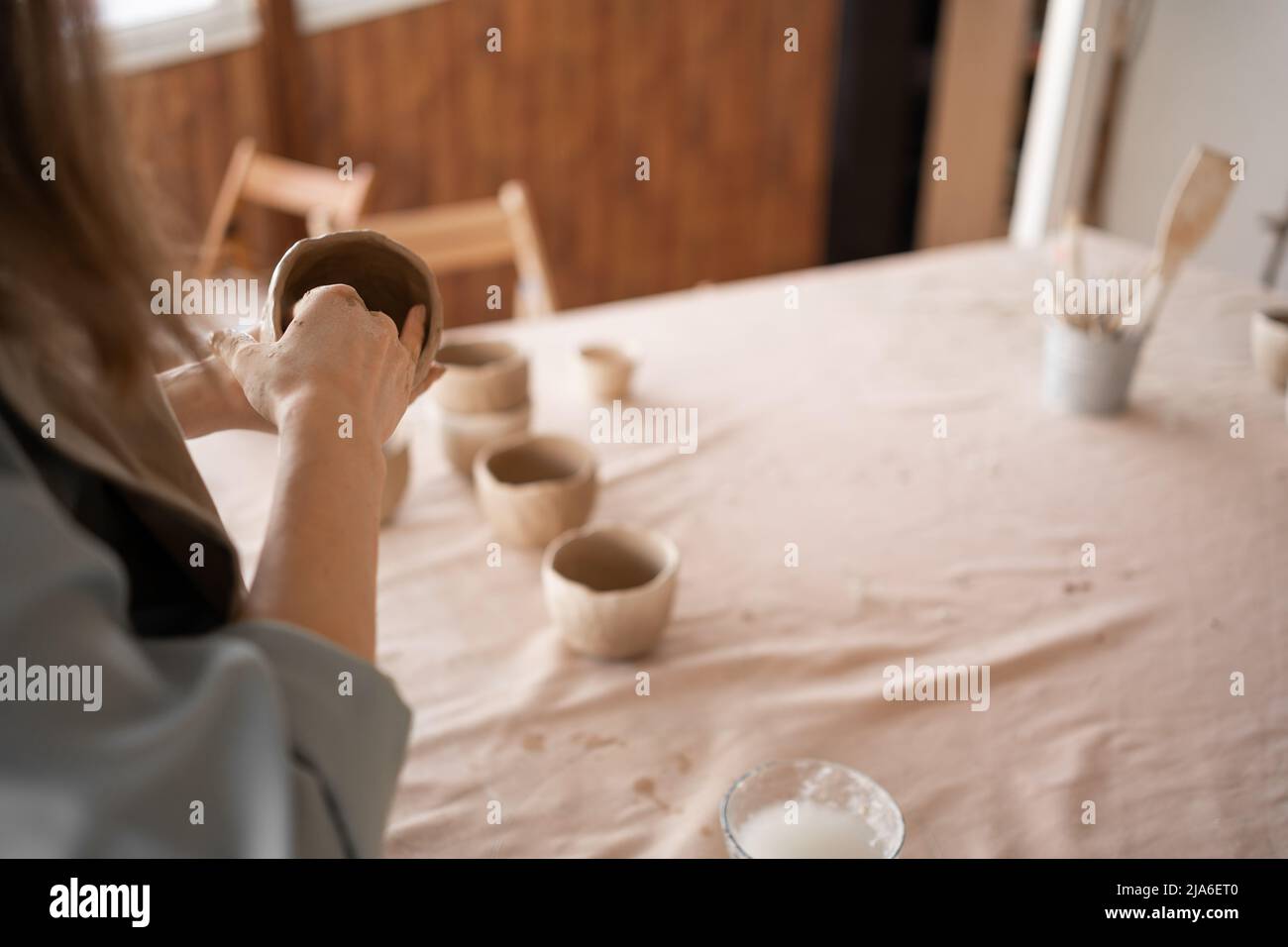 Potter al lavoro. Le mani di Potter in creta formano un vaso in un cerchio. Primo piano di femmina sculpting ciotole da creta bagnata cruda. Foto Stock