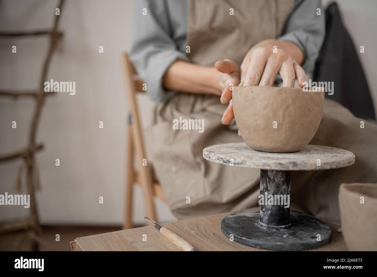 il vasaio femminile crea artigianato fatto a mano. Primo piano di mani che scolpiscono una ciotola di argilla su un tavolo di lavoro in uno studio di ceramica in un laboratorio. Artistico Foto Stock