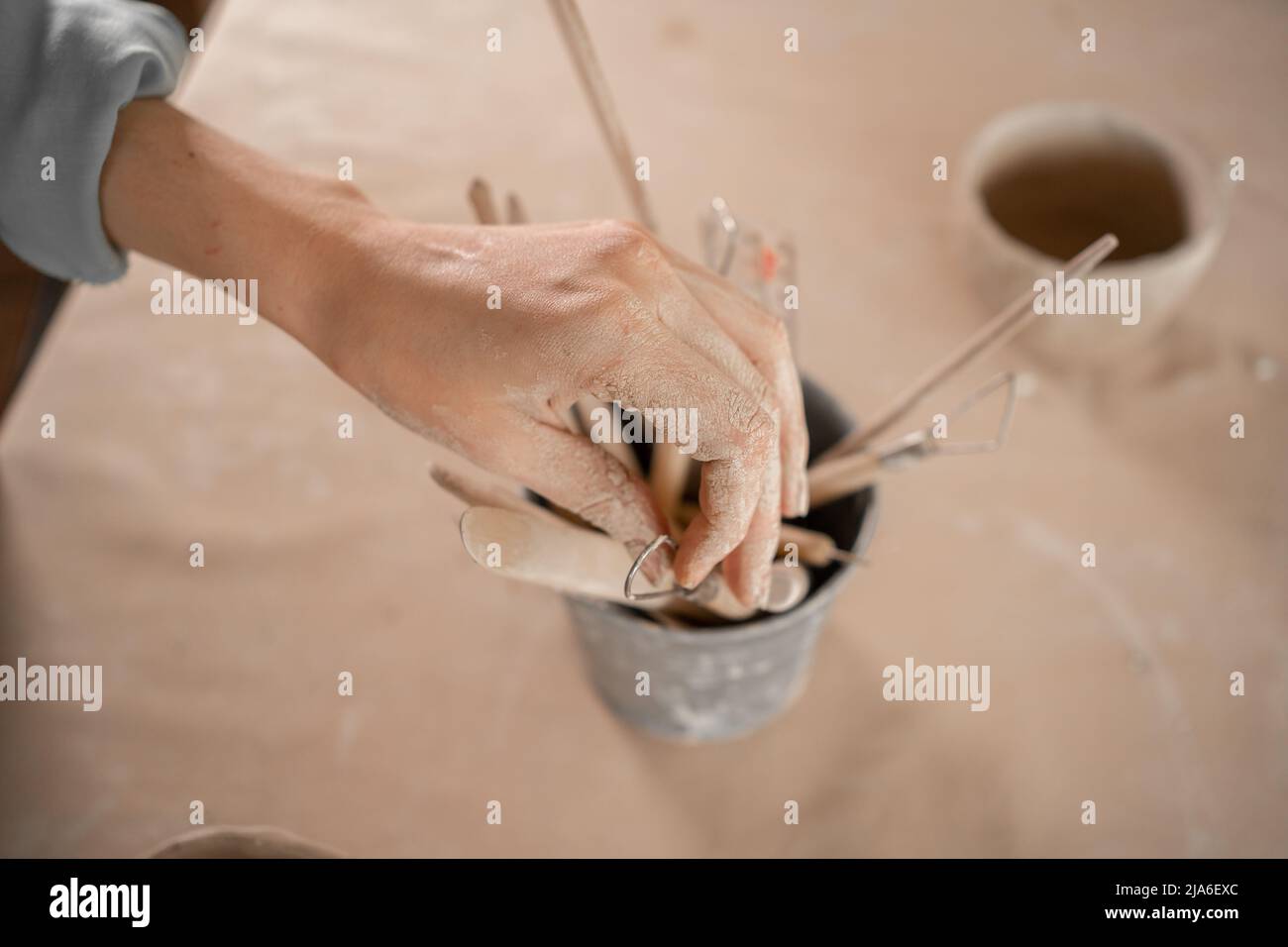 strumenti di scultura in argilla, un set di strumenti per intagliare la ceramica con un manico in legno, le mani femminili dell'artigiano prendere uno di loro. Foto Stock