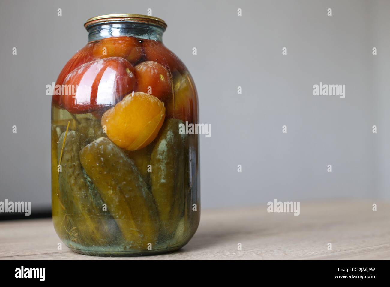 lattina viziata di aggraffatura vegetale. Vaso in vetro con pomodori e cetrioli fatti in casa sottaceto con funghi bianchi e muffa Foto Stock