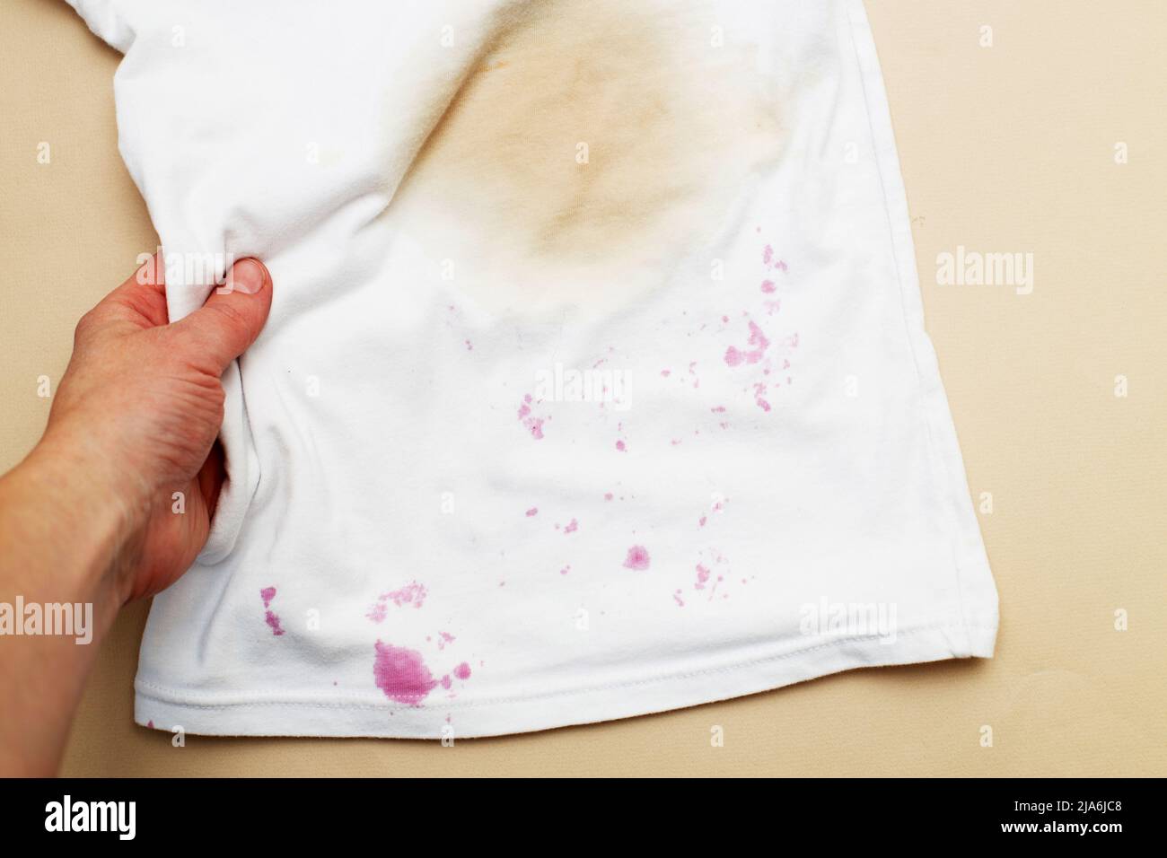 Macchie sporche su una T-shirt bianca da bacche e bere su sfondo marrone. Foto Stock