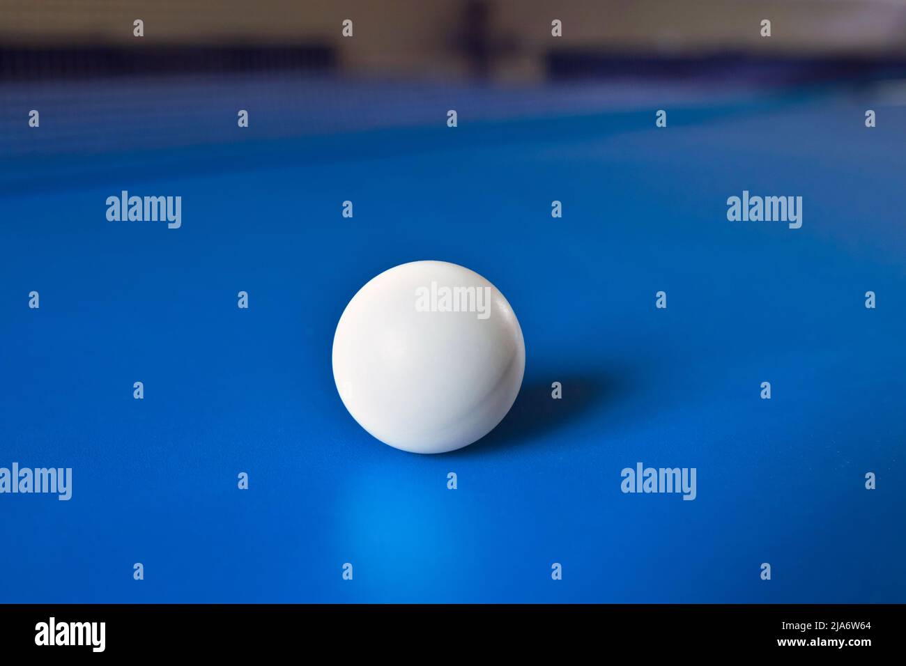 Una palla da tennis bianca su un tavolo blu con il riflesso. Ping Pong, giochi di sport da tavolo. Foto Stock
