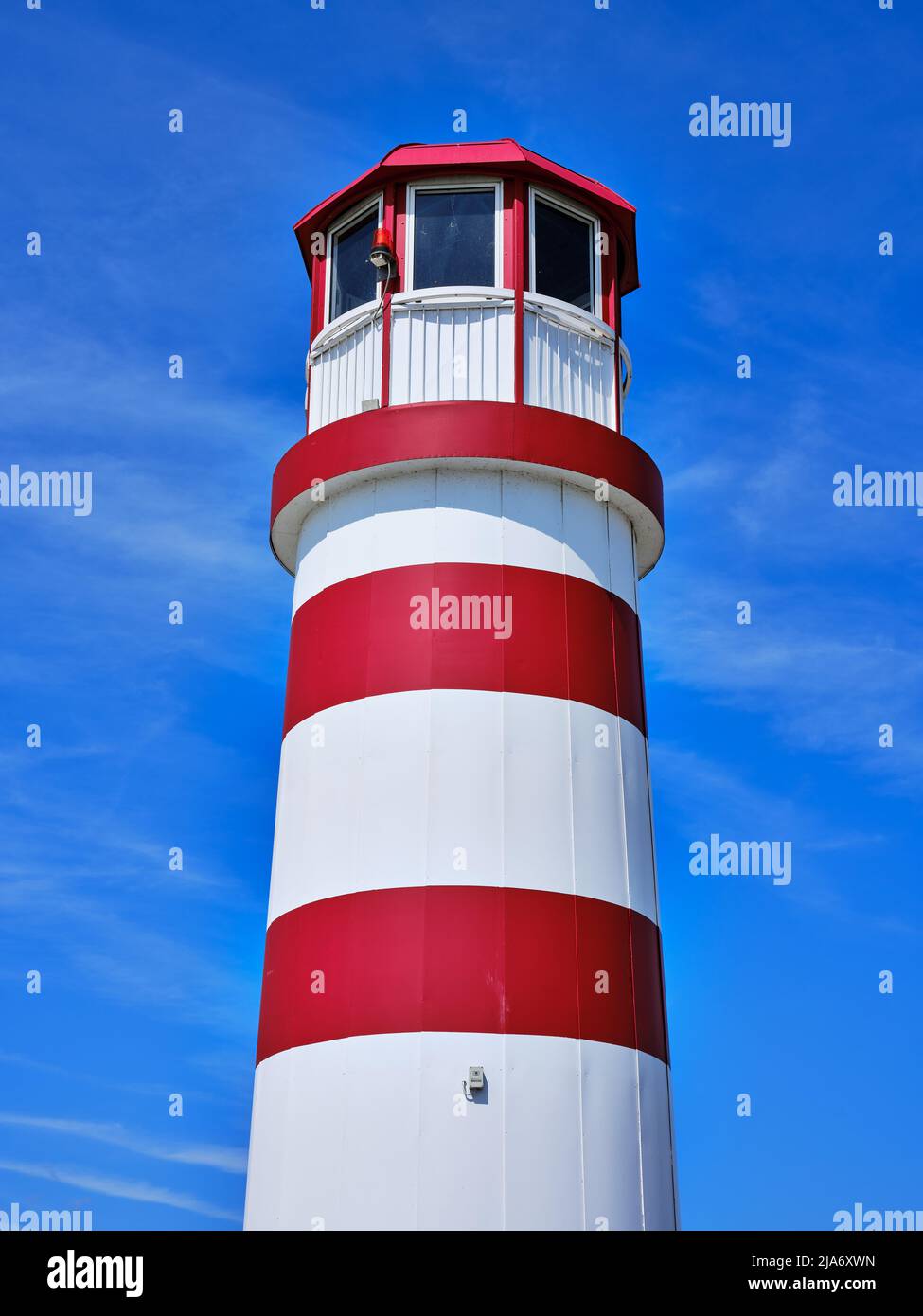 Primo piano del faro rosso e bianco a Podersdorf am SEE, Austria, contro un cielo estivo blu vivace. Foto Stock
