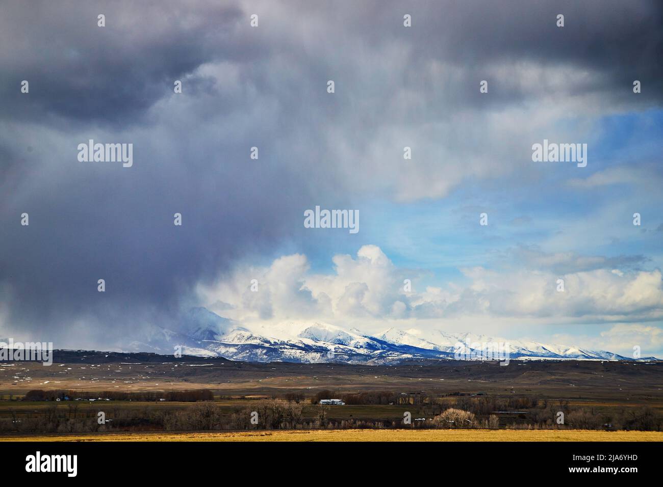 Grandi campi di sorpasso con tempeste scure e bianche montagne innevate Foto Stock