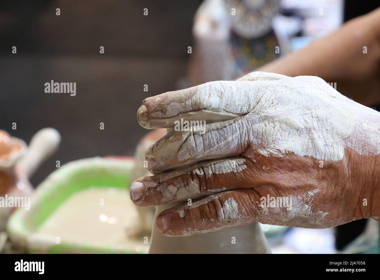 mano del vasaio esperto mentre forma un vaso di argilla s usando la pressione leggera sul materiale con le sue dita sensibili Foto Stock