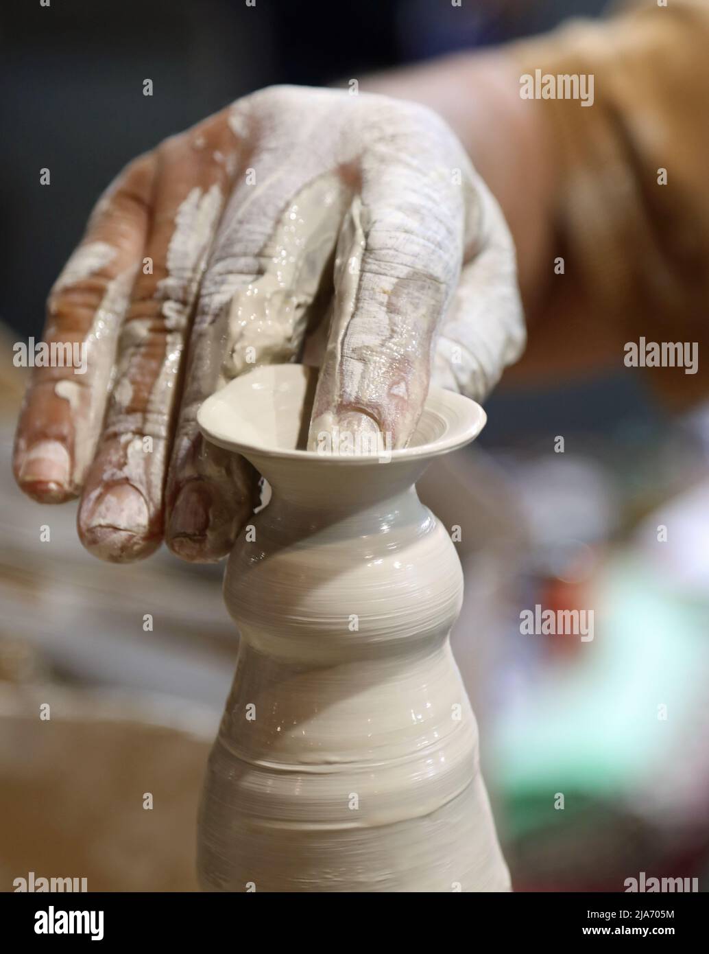 mano del vasaio esperto mentre si forma una pentola di argilla sul tornio che gira usando una leggera pressione sul materiale con le dita sensibili Foto Stock
