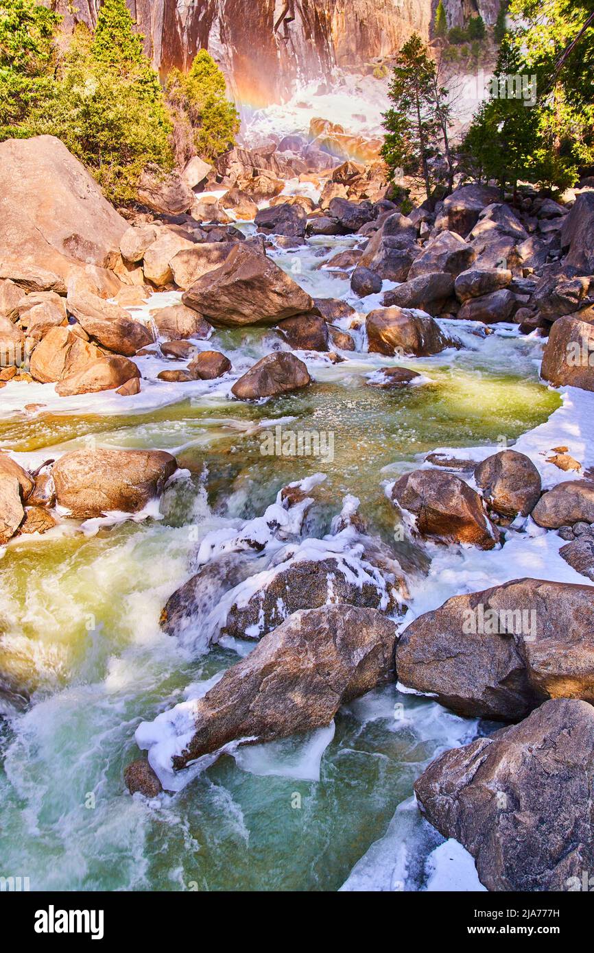 Rocce gelide con acque blu a cascata e arcobaleno sullo sfondo Foto Stock