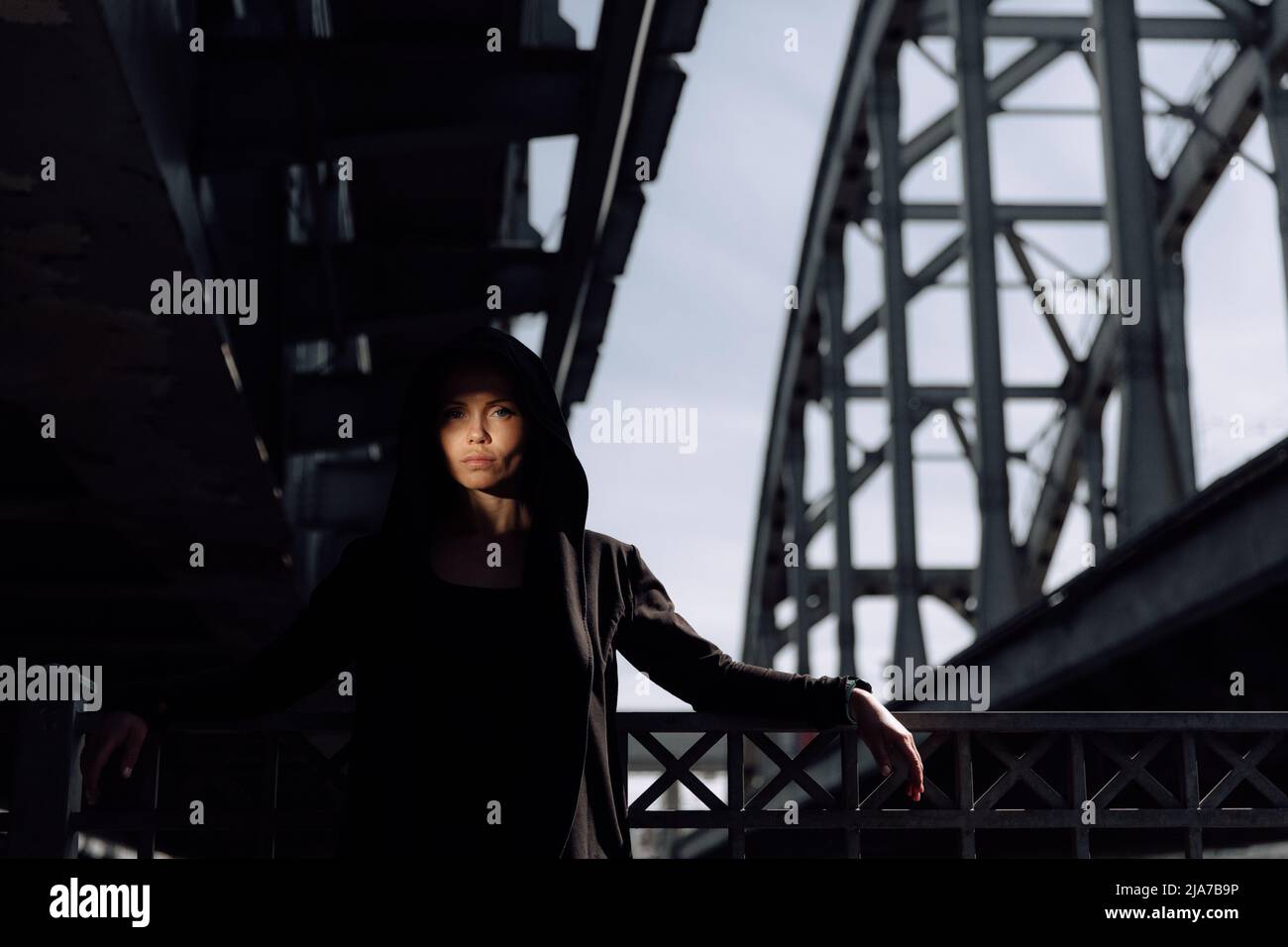 giovane bella ragazza sotto un ponte industriale contro il cielo Foto Stock