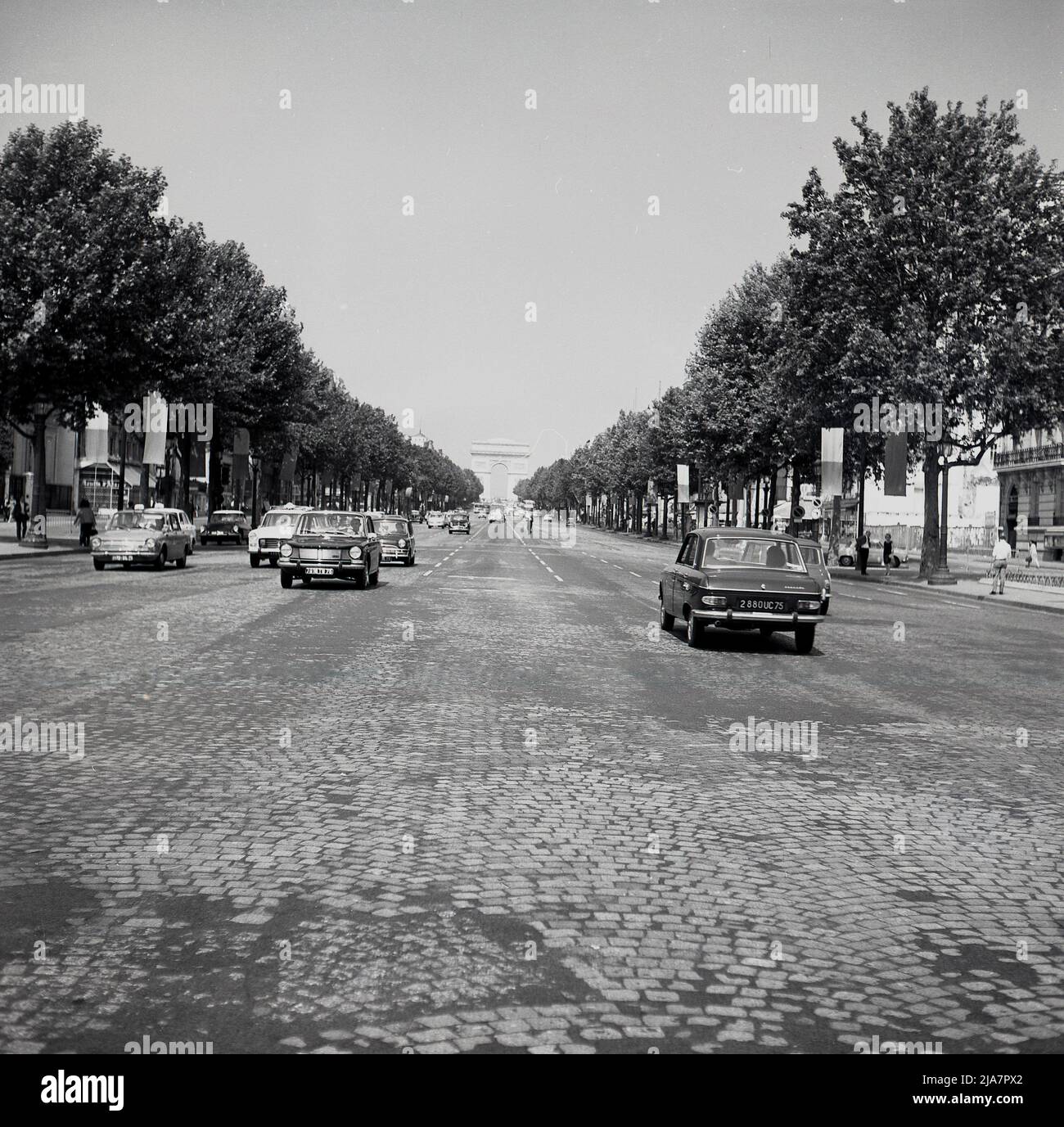 1960s, storico, Parigi, Francia e una vista da questa epoca del famoso viale acciottolato, il Champ-Elysees, un lungo, ampio viale alberato che conduce fino all'Arco di Trionfo, l'imponente arco trionfale, che è un'icona del paese. Foto Stock