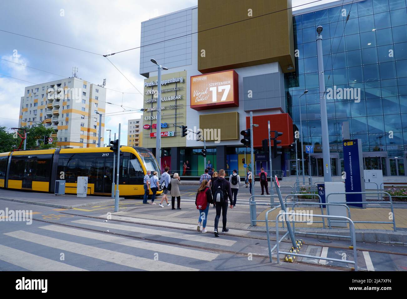 Budapest, Ungheria - 19 settembre 2021: Paesaggio cittadino moderno, attraversamento pedonale e tram giallo di fronte a Etele Plaza Foto Stock
