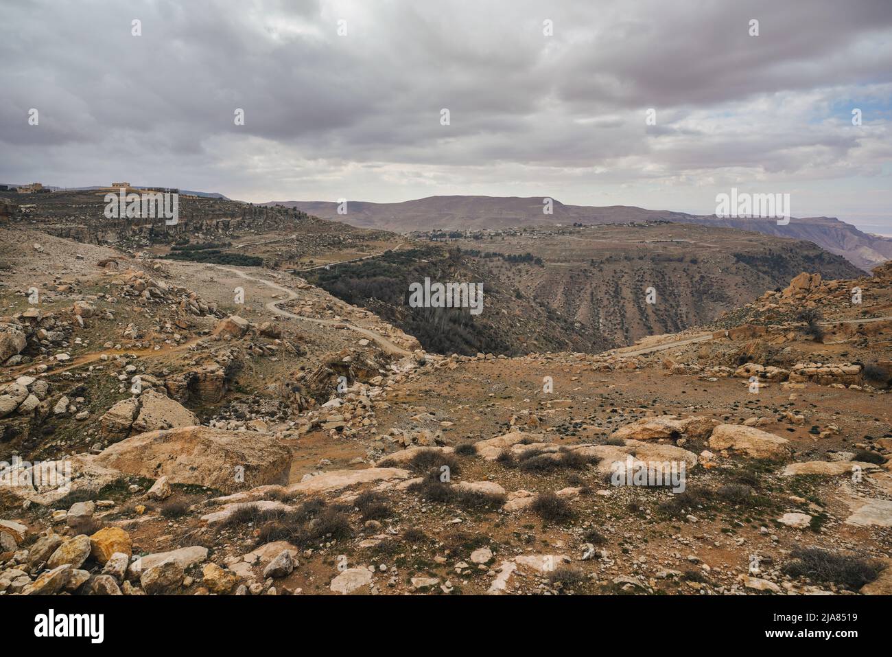 Ampio panorama della riserva della biosfera di Dana in Giordania, nuvole grigie sovrastanti su un grande canyon Foto Stock