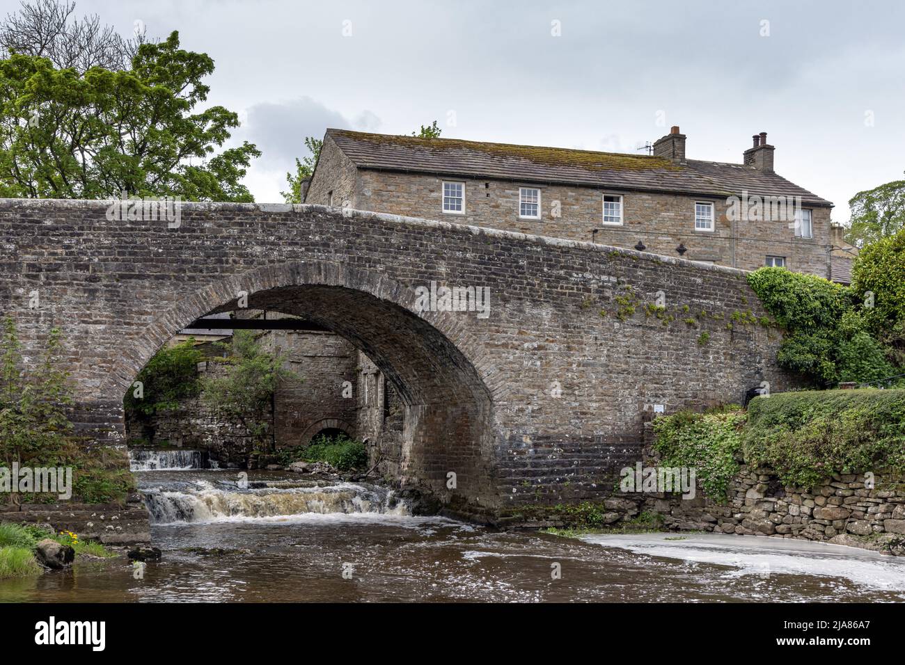 Il pittoresco ponte di pietra sul fiume Bain a Bainbridge, Yorkshire Dales, Inghilterra Foto Stock