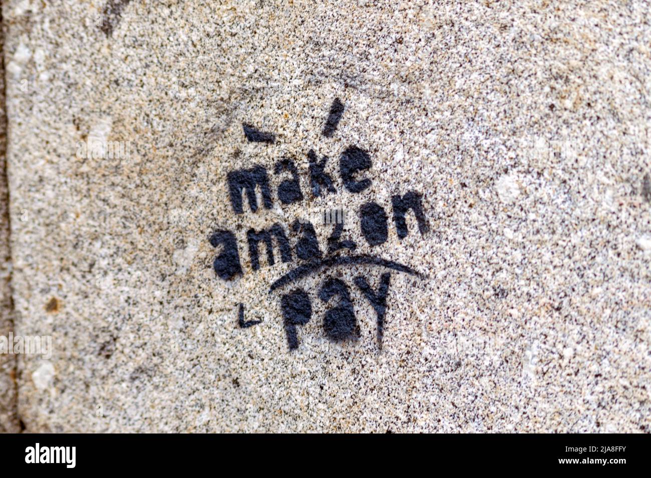 Fare amazon pagare stencil o graffiti su una parete della città. Una forma di protesta contro il grande commercio multinazionale in linea. Le grandi aziende o le società protestano Foto Stock