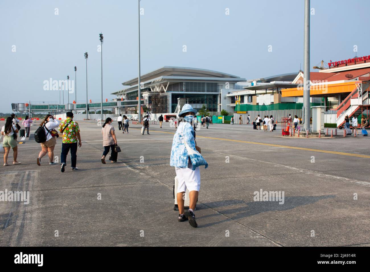 Persone thailandesi e passeggeri stranieri a piedi trasportano o tirano la borsa bagagli giù l'aereo sulla pista andare al terminal all'Aeroporto Internazionale di Muang Khon Foto Stock