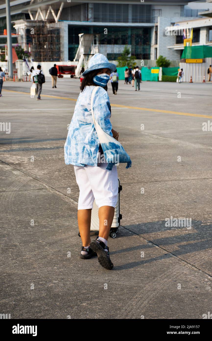 Le donne thailandesi viaggiatori passeggeri che indossano maschera a piedi trasporto o tirare bagaglio borsa dopo l'aereo giù sulla pista andare al terminal buiding a Muang Khon Intern Foto Stock