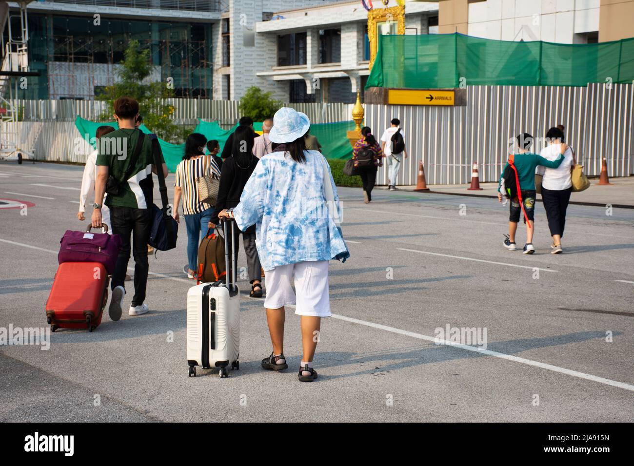 I passeggeri di persone thailandesi e stranieri che camminano trasportano o tirano il bagaglio dopo aver giù l'aereo sulla pista vanno al terminal di Muang Khon Interna Foto Stock