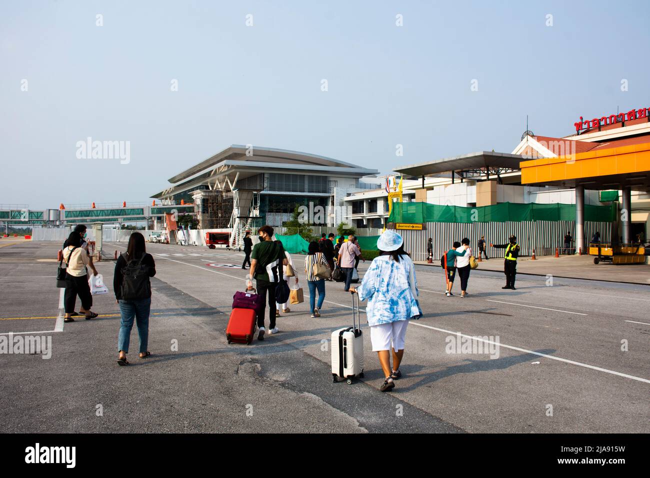 Persone thailandesi e passeggeri stranieri a piedi trasportano o tirano la borsa bagagli giù l'aereo sulla pista andare al terminal all'Aeroporto Internazionale di Muang Khon Foto Stock