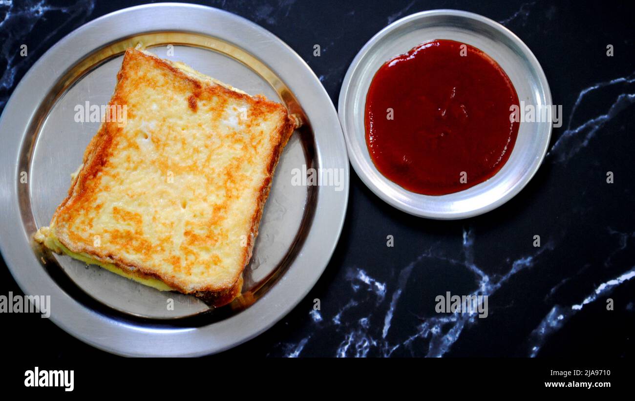 Pane appena cucinato Omelet e salsa di pomodoro rosso sono posti su un piatto d'argento con fondo nero e pronti per servire Foto Stock Pane appena cucinato Omelet e salsa di pomodoro rosso sono posti su un piatto d'argento con fondo nero e pronti per servire Foto Stock