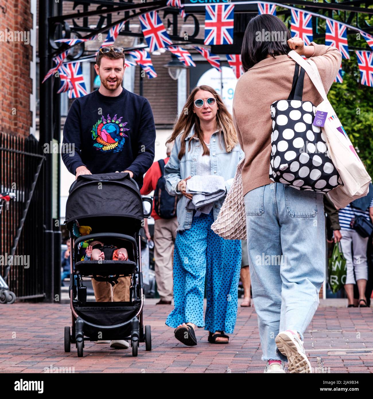 Epsom Surrey, Londra UK, 28 2022 maggio, giovani coppie a piedi spingendo Un passeggino bambino attraverso Market Square Foto Stock