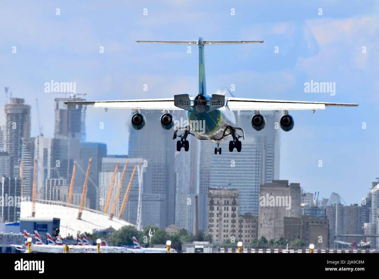 Primo piano vista posteriore di un aereo passeggeri a quattro motori che atterra all'aeroporto di London City Newham con O2 & Arena Canary Wharf a London Docklands Inghilterra UK Foto Stock