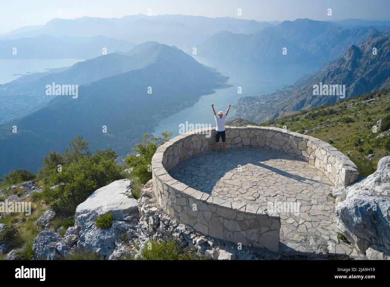 Un uomo alza le mani nella gioia e guarda il paesaggio nel punto di vista, il concetto di successo Foto Stock