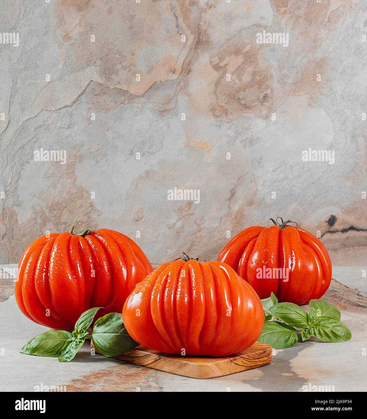 Pomodori e basilico freschi Raf Coeur De Boeuf su sfondo marrone, concetto rustico, foto di scorta, spazio per il testo Foto Stock