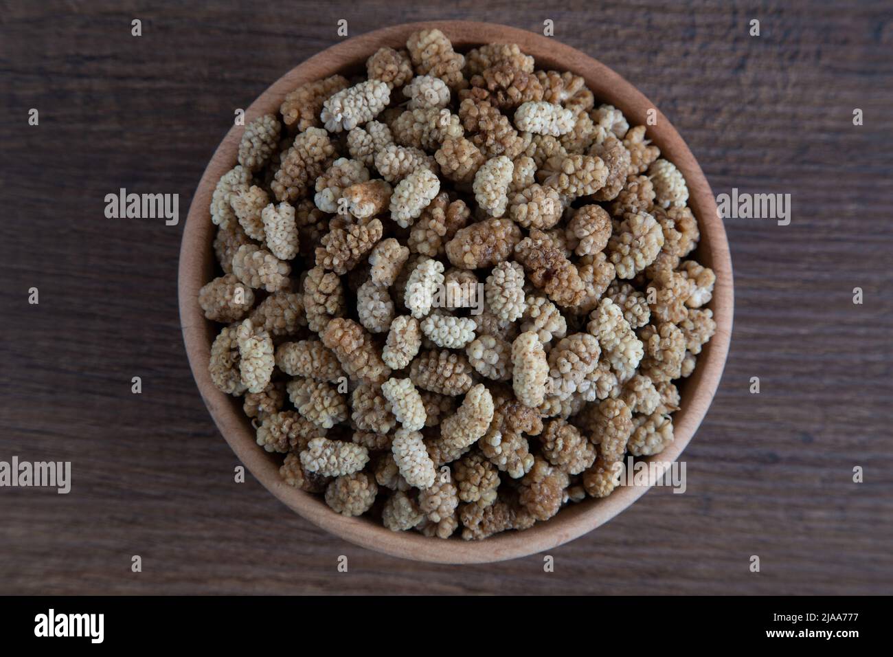 Ciotola piena di gelso secco su sfondo di legno Foto Stock