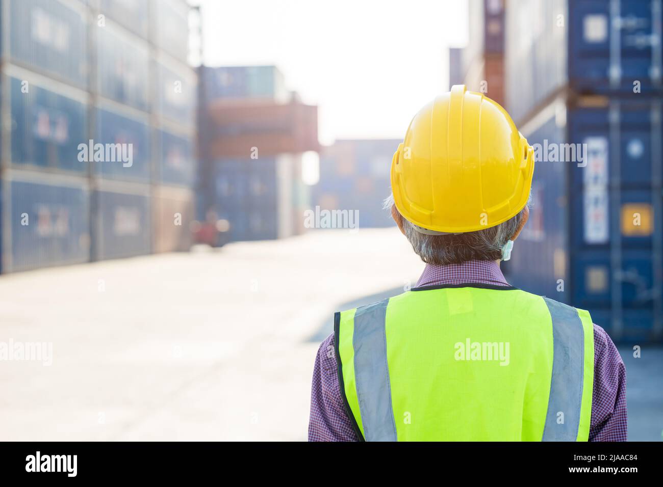visione del lavoratore senior che guarda il cantiere del porto di spedizione del carico del luogo di lavoro dalla vista posteriore con spazio per la copia. Foto Stock