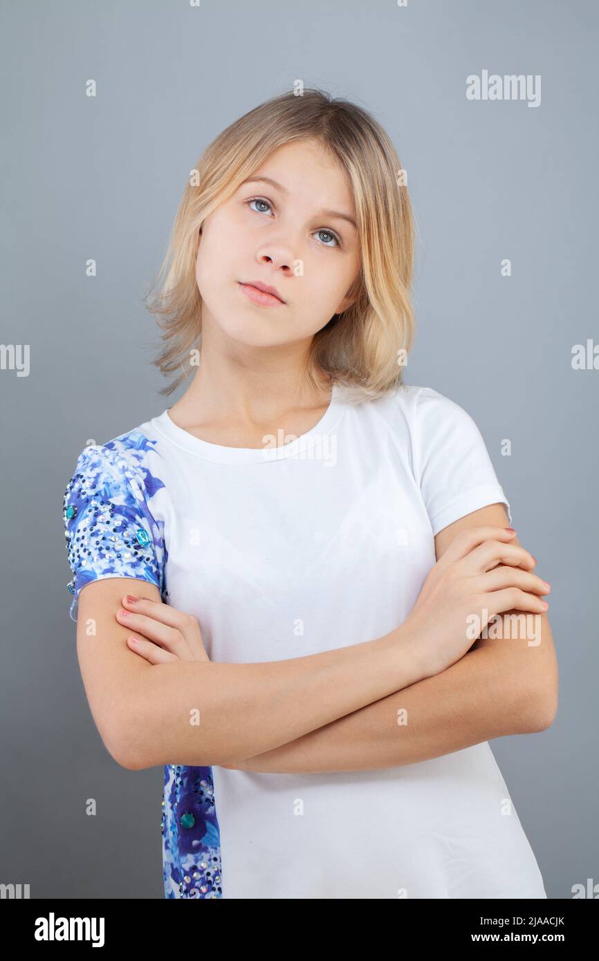 Ragazza giovane e carina e pensiva che pensa e guarda su sfondo grigio Foto Stock