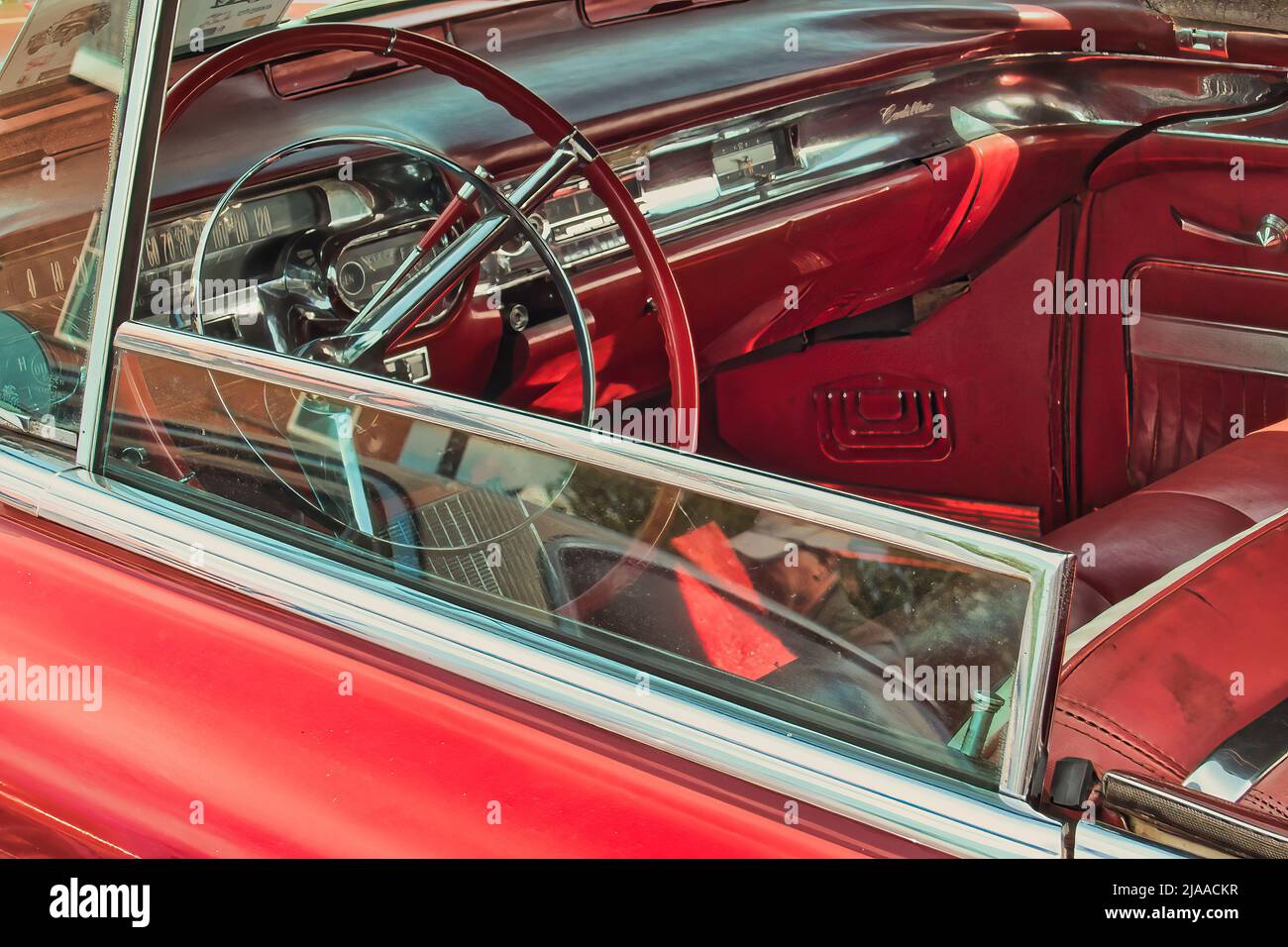 Interno con cruscotto e volante di un'auto d'epoca Cadillac coupé deville convertibile anni '50, in pelle cromata lucida e rossa Foto Stock