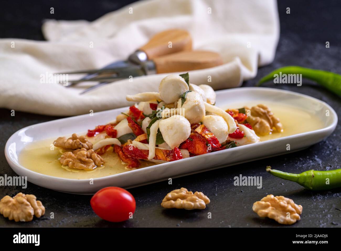 Formaggio per la colazione preparato appositamente. Uno speciale piatto di formaggi preparato con olio d'oliva, verdure, noci e formaggi. Primo piano Foto Stock