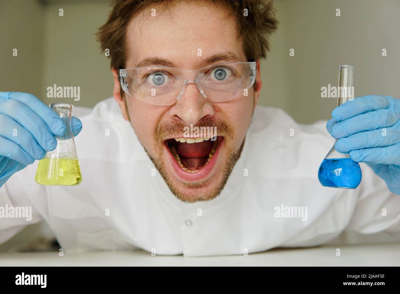 Impazzito chimico pazzo che tiene provetta con il suo successo esperimento in laboratorio. Foto Stock