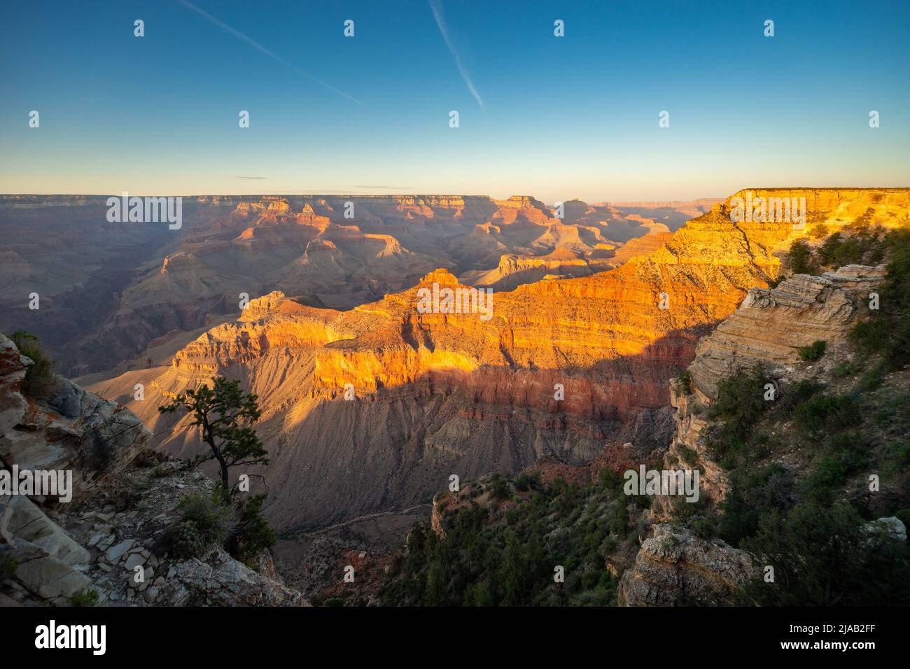 Grand Canyon South Rim, Arizona, Stati Uniti. Il sole tramonta dietro di lanciare un bagliore arancione sulla vista del canyon Foto Stock