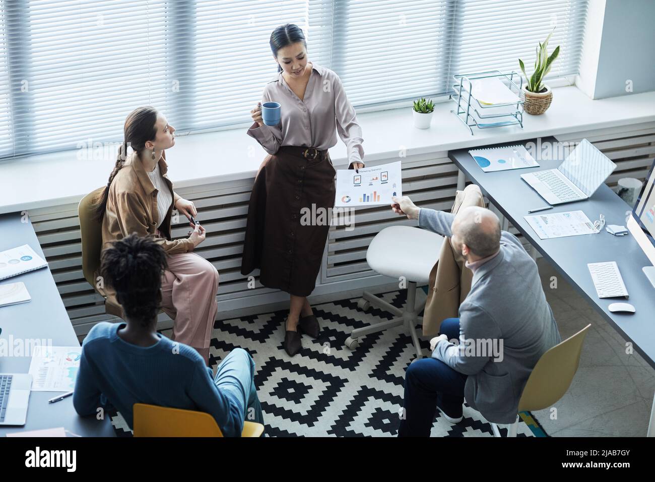 Visualizzazione ad alta angolazione presso diversi gruppi di persone aziendali che brainstorming idee di progetto mentre lavorano insieme in ufficio Foto Stock