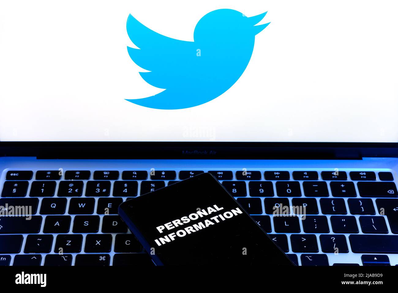 Parole INFORMAZIONI PERSONALI visualizzate sullo smartphone e logo Twitter su un notebook sfocato dietro di esso. Concetto. Stafford, Regno Unito, 29 maggio 2022 Foto Stock