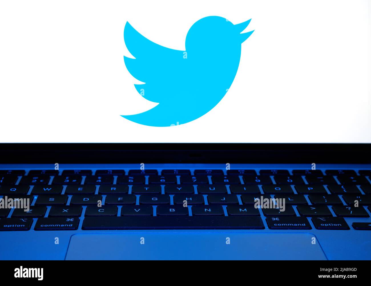 La tastiera è accesa con una luce blu. Notebook con logo Twitter sfocato. Concetto. Stafford, Regno Unito, 29 maggio 2022 Foto Stock