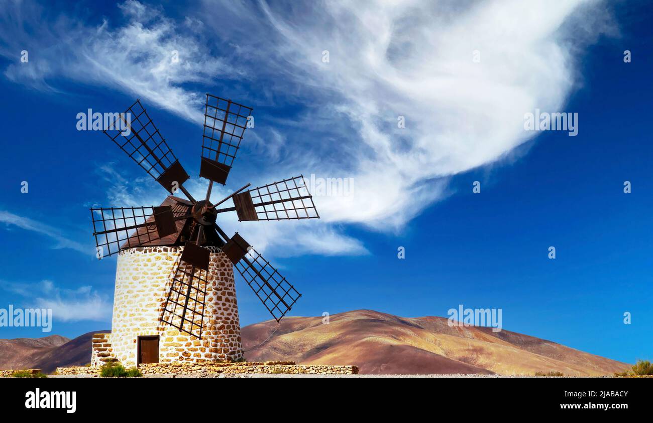 Isolato tradizionale mulino a vento rotondo spanisch pietra (Molino de Tefia), secco aride paesaggio collinare, blu cielo bianco nuvola - Fuerteventura, Isole Canarie Foto Stock