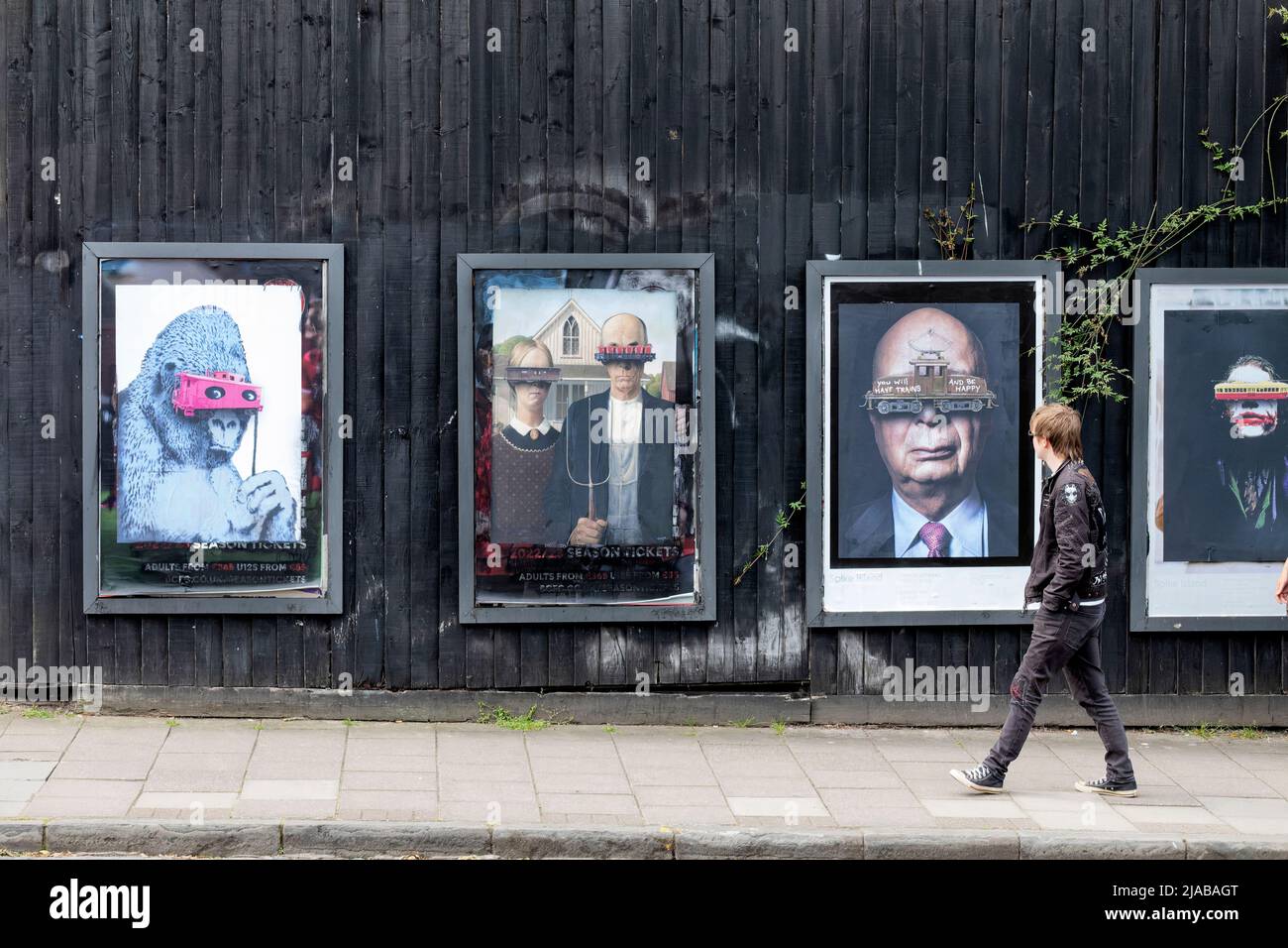 Bristol, Regno Unito. 28th maggio 2022. Un membro del pubblico cammina accanto a una serie di poster incorniciati e iconici su North Street, Bedminster, Bristol Foto Stock