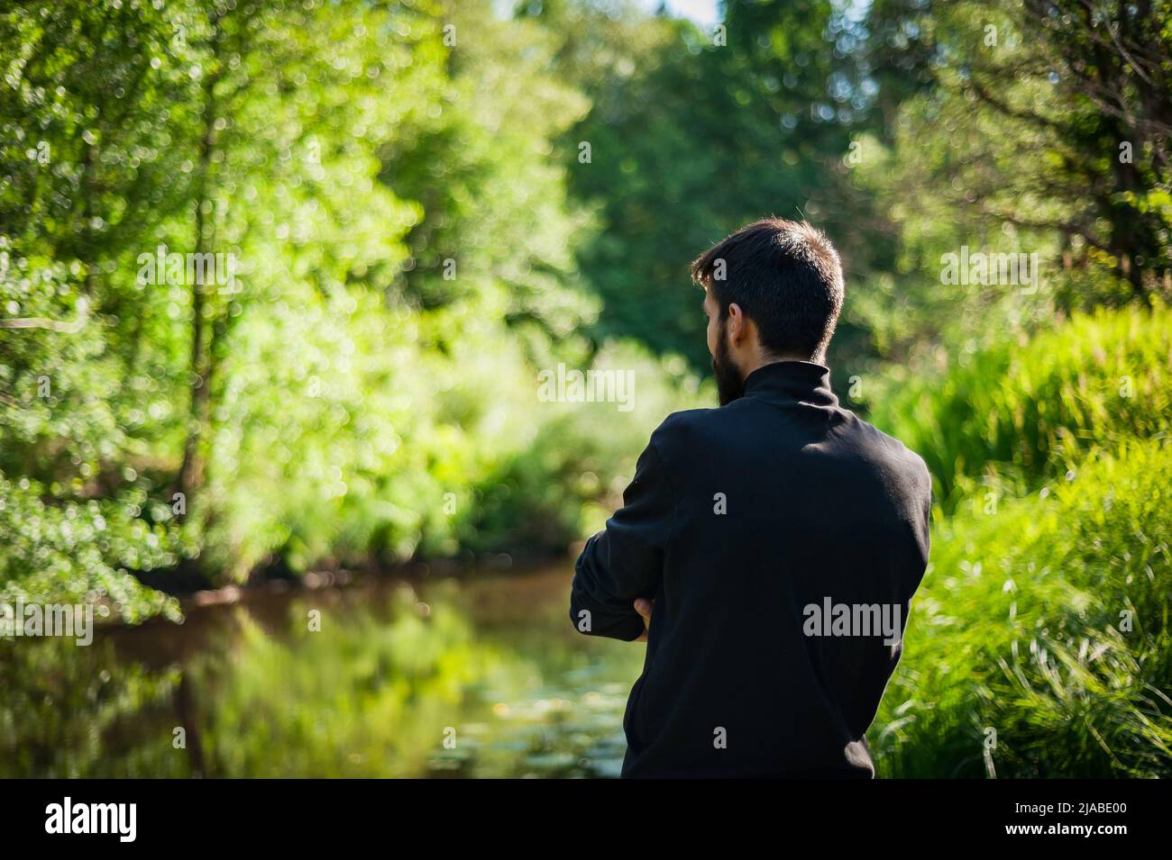 Silhouette di un uomo dal retro al tramonto. Il modello maschile torna alla natura Foto Stock