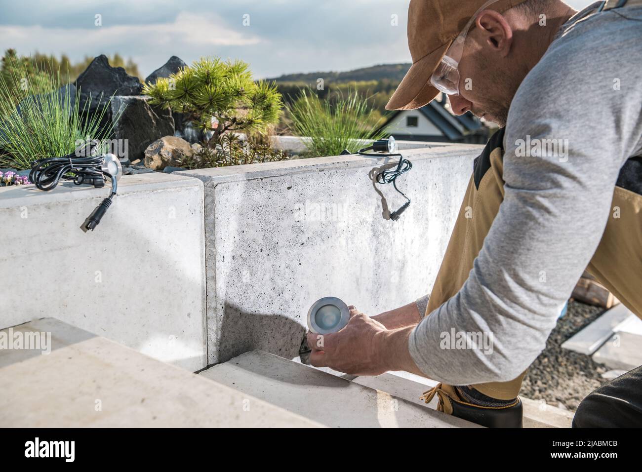 Tecnico del paesaggio caucasico nel suo 40s Installazione di illuminazione da giardino all'aperto lungo scale in cemento. Settore paesaggistico. Foto Stock