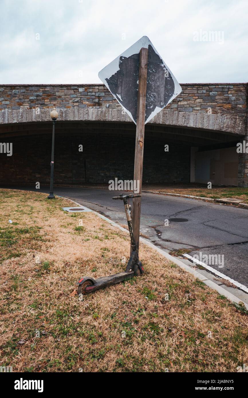 Un abbandonato e-scooter condiviso accanto a un cartello stradale a Washington, D.C. Foto Stock