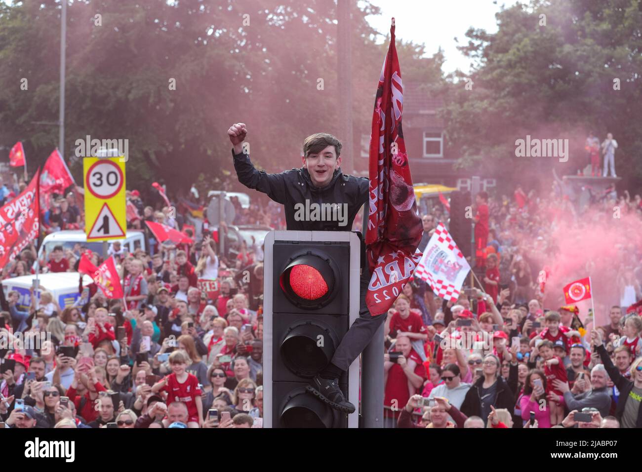 Un sostenitore sale su un semaforo mentre la squadra del Liverpool FC festeggia durante la sfilata di autobus scoperto attraverso la città dopo aver vinto sia la Carabao Cup che la fa Cup nella stagione 2021/22 Foto Stock