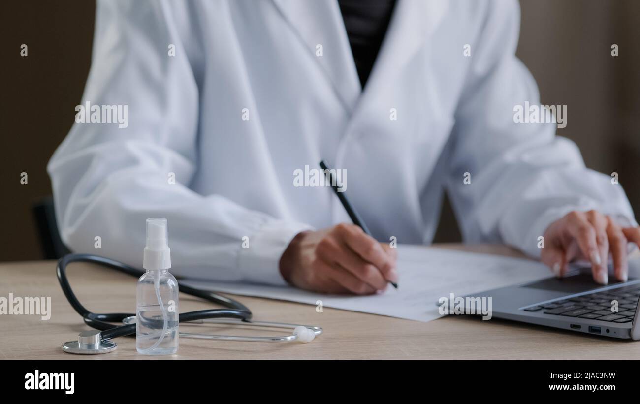 Primo piano su mano femminile irriconoscibile medico professionista scrittura prescrizione di documenti di avviso alla scrivania con attrezzatura medica terapista donna Foto Stock