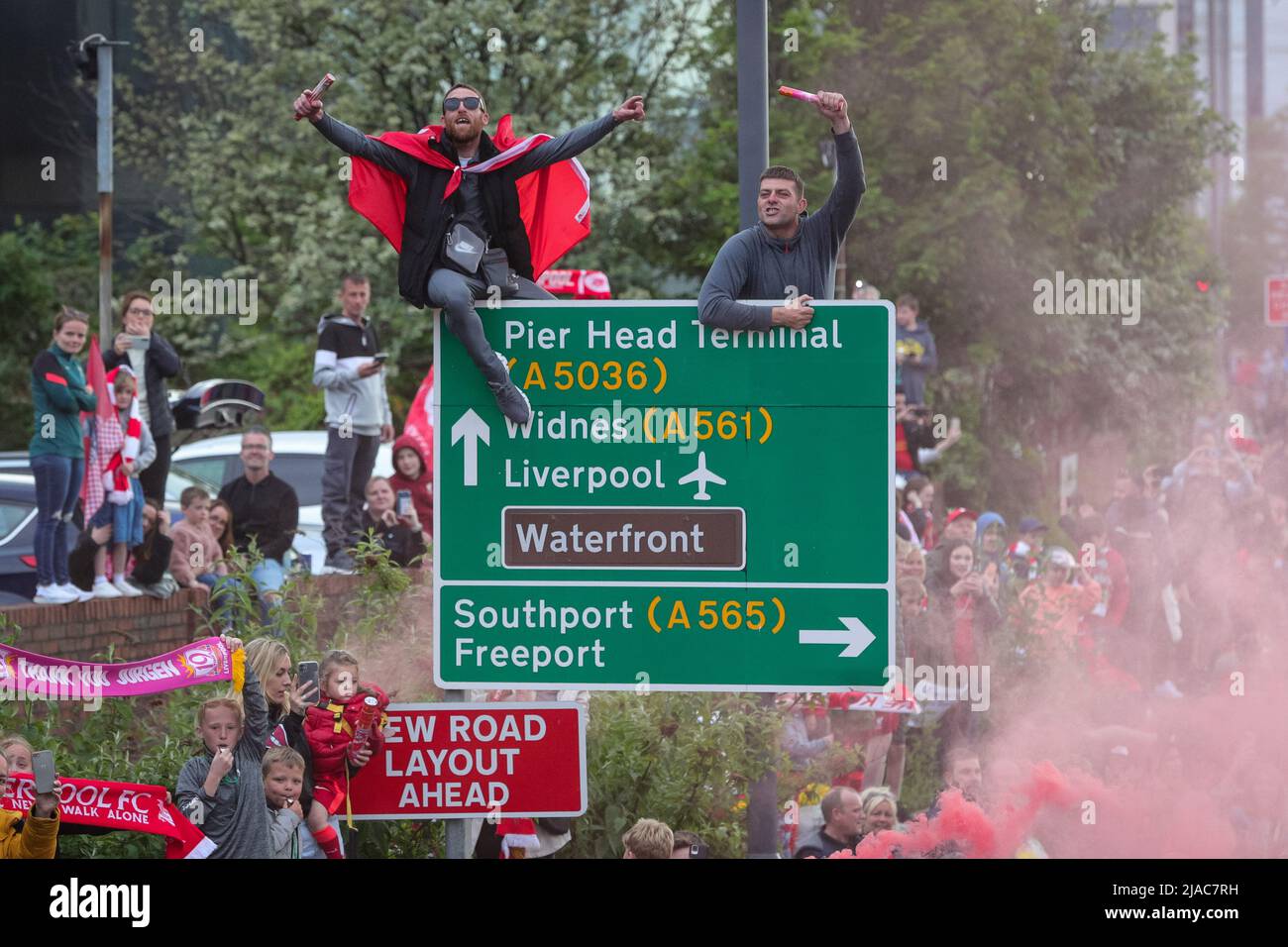 I tifosi salgono sui cartelli stradali e sulle serie di razzi mentre la squadra del Liverpool FC festeggia durante la sfilata di autobus scoperto attraverso la città dopo aver vinto sia la Carabao Cup che la fa Cup nella stagione 2021/22 Foto Stock